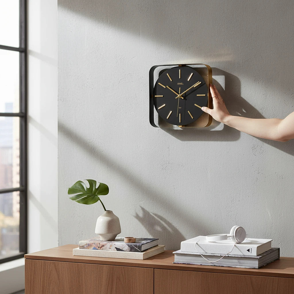 Standuhren.com 🕰️ AMS F5585 Funkwanduhr mit schwarzem Metallgehäuse und elegantem Zifferblatt in Messingoptik an Wand